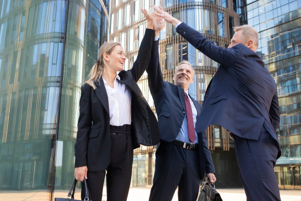 three cheerful businesspeople giving five smiling confident happy colleagues celebrating successful deal together standing outdoors rising hand up teamwork partnership concept 74855 7845